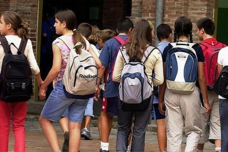 Estudiantes con mochilas, llegando a la escuela